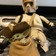 A Star Wars Scout Trooper carries Baby Yoda in a bag.